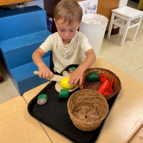 Young male student playing with pretend food toys.